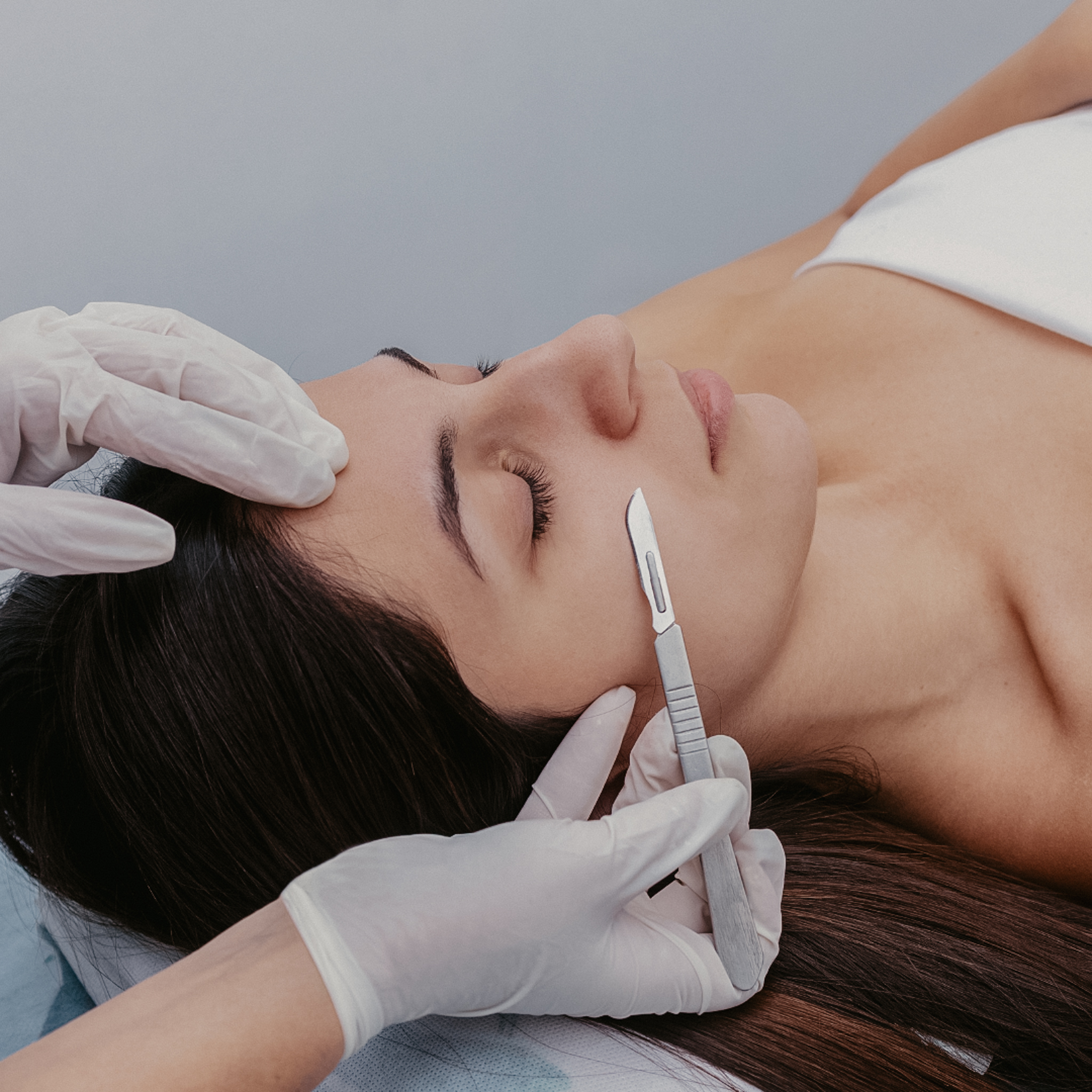 woman laying down with a white towel on getting dermaplaning